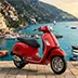 A scooter in the foreground with the iconic colorful houses of Positano in the background
